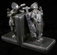 A pair of silver-plated copper bookends, each with a figurine of a young male golf caddie