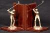 A pair of wooden bookends with varnished finish and a brass golfing statue figure on each