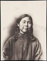Photograph of an Eskimo girl with braided hair, wearing a cloth dress