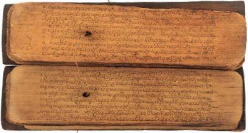 Handwritten religious text on palm leaves, bound in the traditional style with string through holes in the leaves