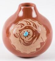 Red pot with carved design and attached turquoise stone