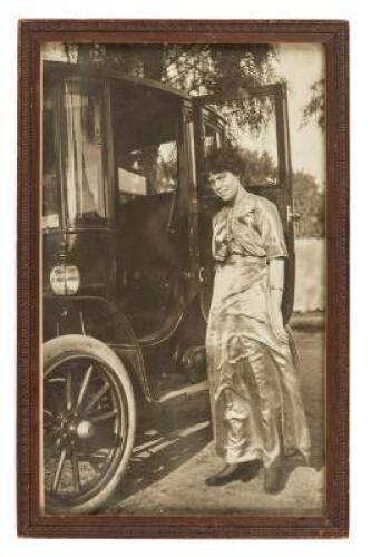 Original photograph of a young woman standing next to an early electric-powered car