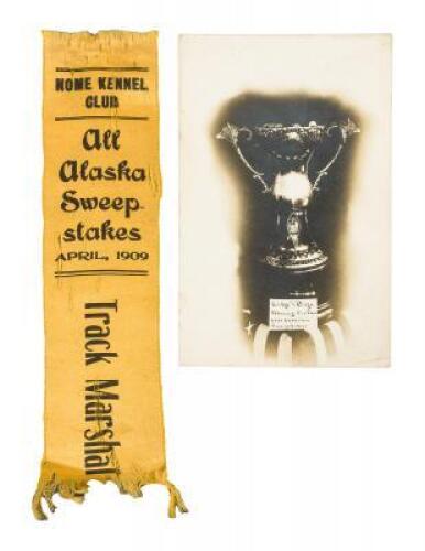 Ribbon for the Track Marshal at the Nome Kennel Club All Alaska Sweepstakes, April 1909, along with a real photo postcard showing the prize cup for the winner