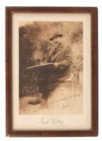 Inscribed photo of the seated artist at work and original ink sketch of a figure on horseback gazing at a beached boat.