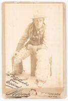 Cabinet card portrait of William S. Hart with chaps and gloves, sitting on posing prop