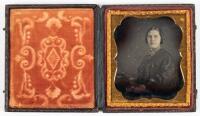 Daguerreotype of seated woman, hands folded with faint highlighting of gold jewelry