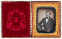 Daguerreotype portrait of seated gentleman resting right arm on posing table