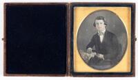 Daguerreotype of seated gentleman, in fancy checkered bow tie with arm resting on posing table.
