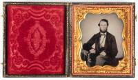 Ambrotype portrait of seated gentleman with arm resting on posing table