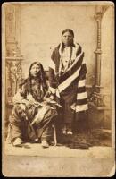 Photograph of two Indians in studio setting, one holding a revolver