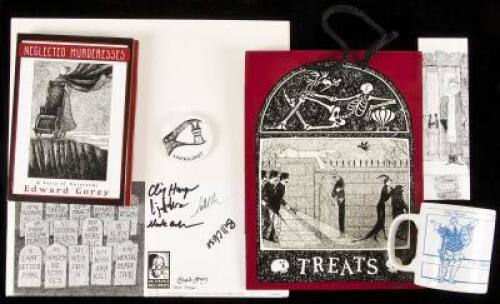 Lot of Edward Gorey collectibles, including buttons, mugs, shirts, and calendars