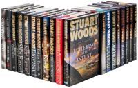 Shelf of Stuart Woods mysteries many featuring Stone Barrington and Holly Barker