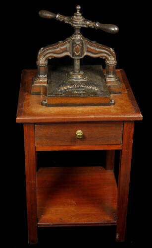 Cast iron French nipping press mounted on antique oak and walnut stand with a single drawer