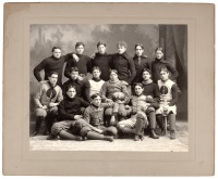 Large photograph of 15 young men seated and standing together, one holding a large football with "97" painted on it