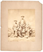 Large photograph of three men seated on rocks, perhaps members of a surveying party