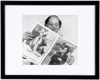 Photograph of Allen Ginsberg holding a newspaper with Leonard Cohen on the cover