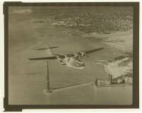 Photographic negative of a flying boat above the Golden Gate Bridge during construction