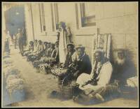 Silver photograph of Hawaiian flower sellers seated against a wall.