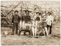 Vintage albumen photograph of four men standing in frnt of a partially consructed building, with numerous saws, planes and other implements on display