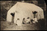 Vintage photograph of family in front of grass hut