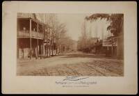 Albumen photograph of a street in Sonora, California, lined with wooden building and bare trees